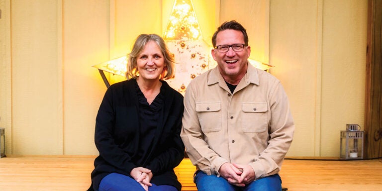 A couple sitting in front of a lit star in a barn like setting.