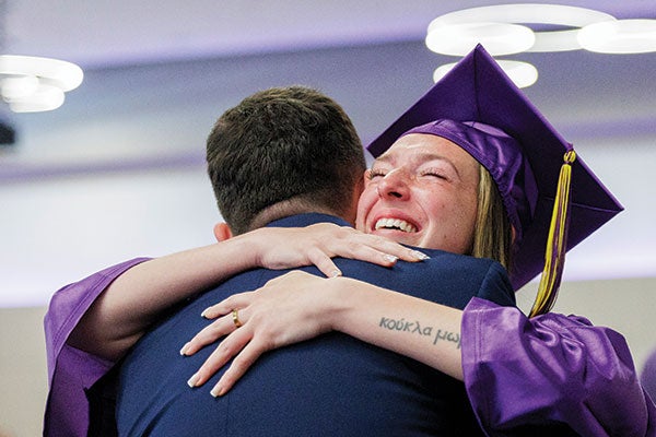 A graduating student hugs a man in a suit.