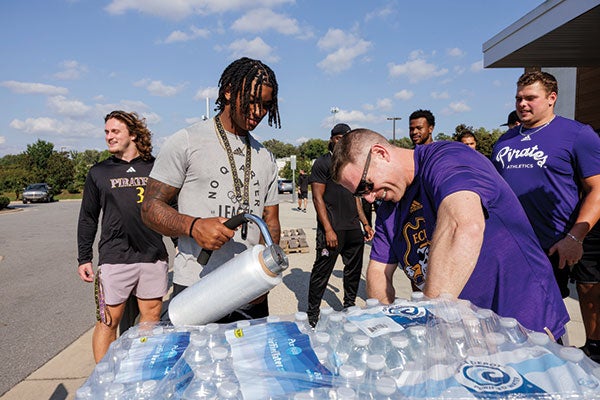 A group of men in purple shirts gathered around a water cooler, engaging in conversation and sharing ideas.