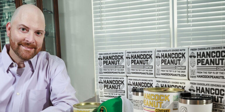 A man seated at a table surrounded by various boxes of peanuts, contemplating his next culinary creation.