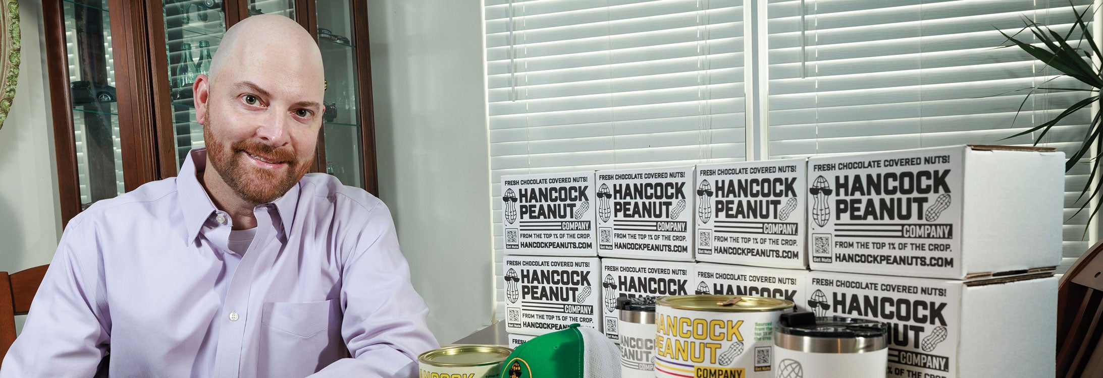 A man seated at a table surrounded by various boxes of peanuts, contemplating his next culinary creation.