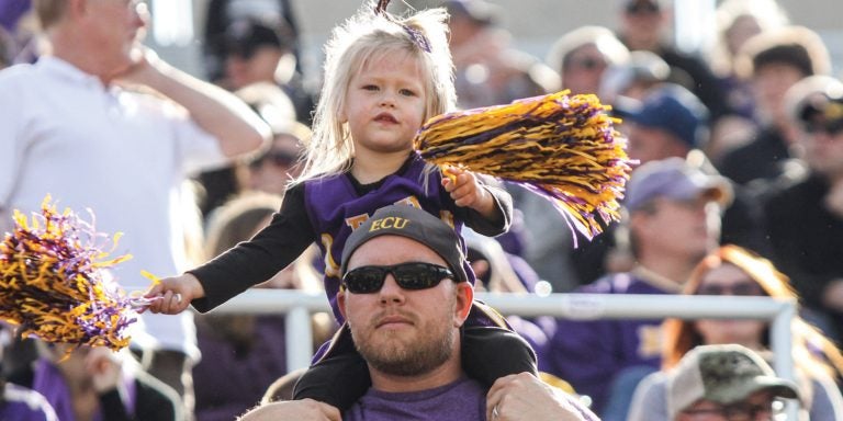 Fans dressed in ECU merchandise at a game.