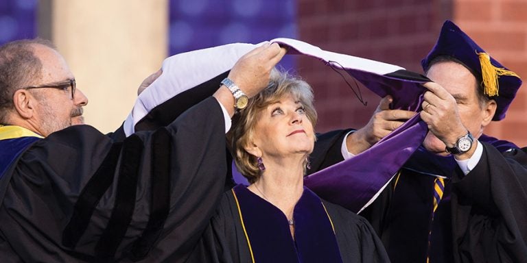 ECU Provost Ron Mitchelson, left, and Kieran Shanahan, chair of the ECU Board of Trustees, place a hood on keynote speaker Linda McMahon, administrator of the U.S. Small Business Administration, who received a honorary doctor of humanities degree.