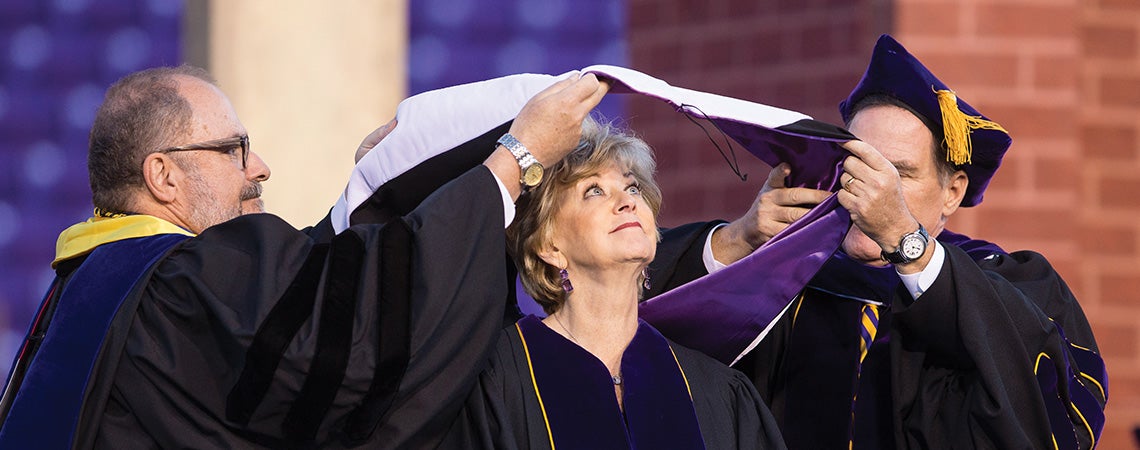 ECU Provost Ron Mitchelson, left, and Kieran Shanahan, chair of the ECU Board of Trustees, place a hood on keynote speaker Linda McMahon, administrator of the U.S. Small Business Administration, who received a honorary doctor of humanities degree.