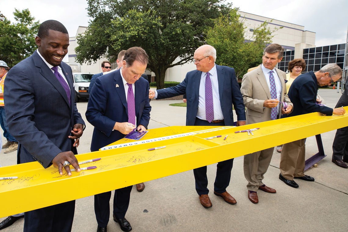 From left, ECU football coach Scottie Montgomery, ECU board chair Kieran Shanahan, trustees Max Joyner Jr. and Kel Normann and trustee Bob Plybon sign the final beam July 12 during the “topping out” ceremony for construction at Dowdy-Ficklen Stadium. Catherine Staton is in the background. The first phase of the $60 million project, the renovation of the first floor of the Ward Sports Medicine Building, was scheduled to open Aug. 1.