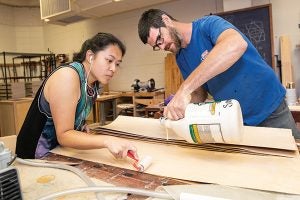 ECU senior Christy Vang and instructor Judd Snapp glue layers of veneer that will eventually become a skateboard.