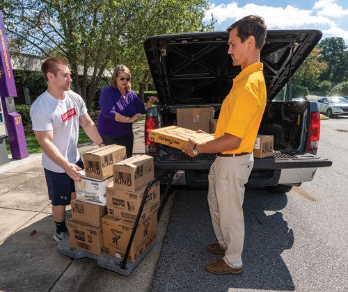 Junior business major Davis Basden and Sharon Paynter and Brandon Morrison of the Division of Research, Engagement and Economic Development unload donated food Sept. 18 at the Willis Building. Todd Burdick ’96 of Affinity Group, a Raleigh food marketer, donated the food. 
