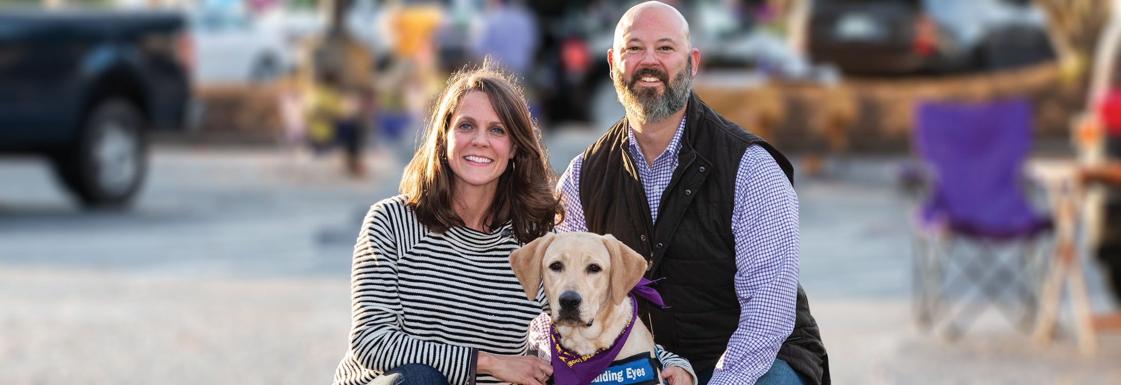 Carlton and Meghan Blanton bring future guide dogs to ECU football games to help train them to assist people with vision loss.