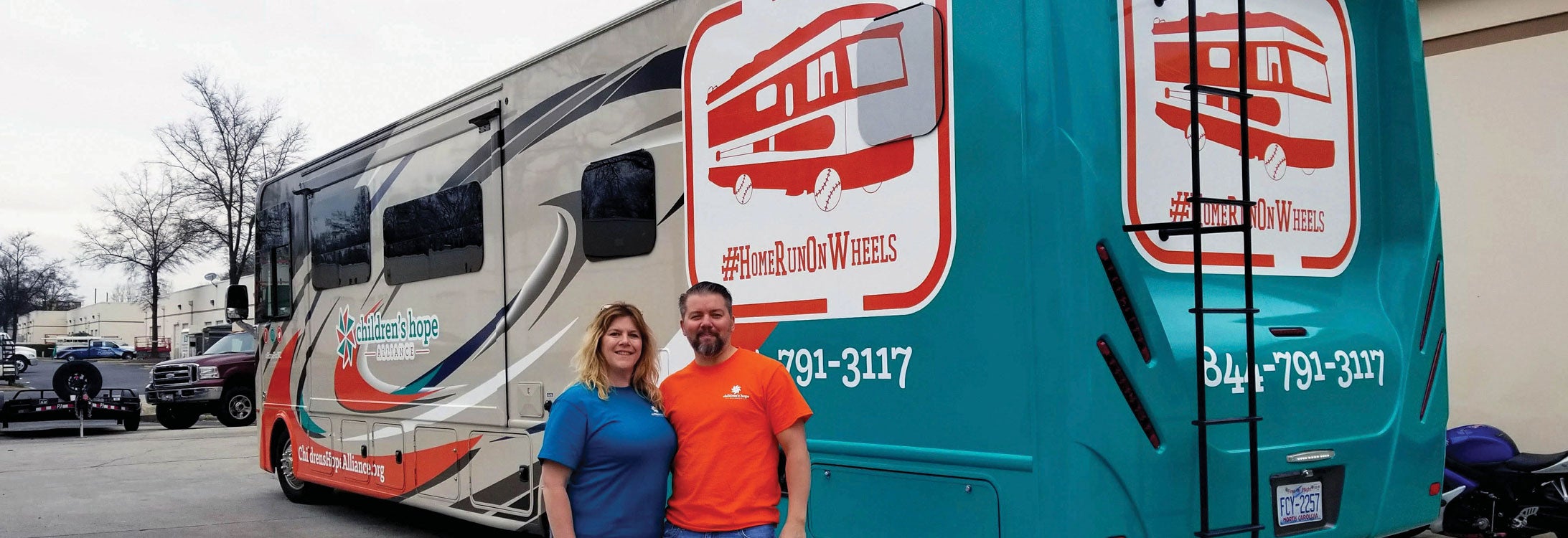 Ron and Patti Clements pose in front of the RV they drove
around the country and to Canada, taking foster children to
Major League Baseball games.