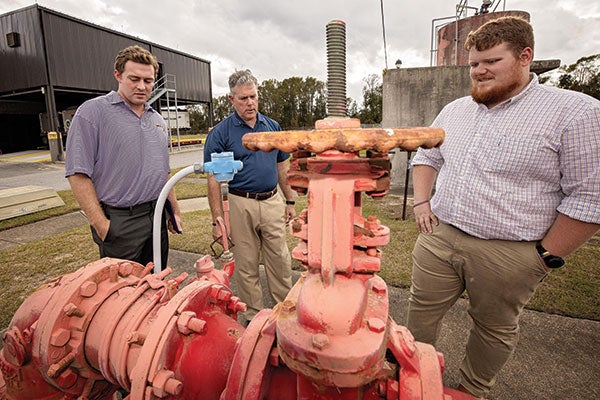 Student Morgan Ensley, Jason Manning, superintendent of the GUC treatment plant, and student Dawson Reese look over equipment at the plant.