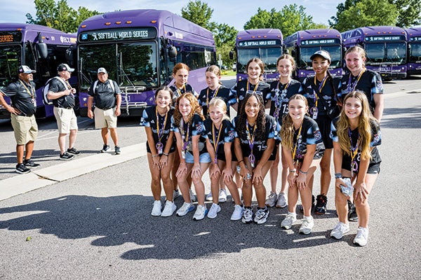 A group of girls in purple uniforms smiling and posing together for a photograph. 