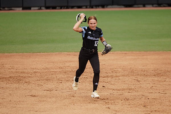 A softball player in action, skillfully throwing the ball with focus and determination on the field.