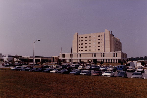 A large building with numerous cars parked in front, showcasing a busy and well-utilized space. 