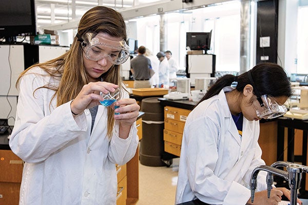 Two female students looking through microscopes.
