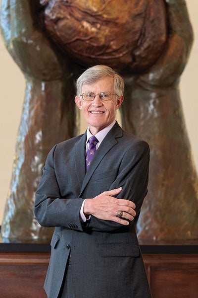 A man in a suit crosses arms.