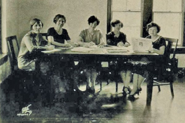 An old photo of a number of women at a atable