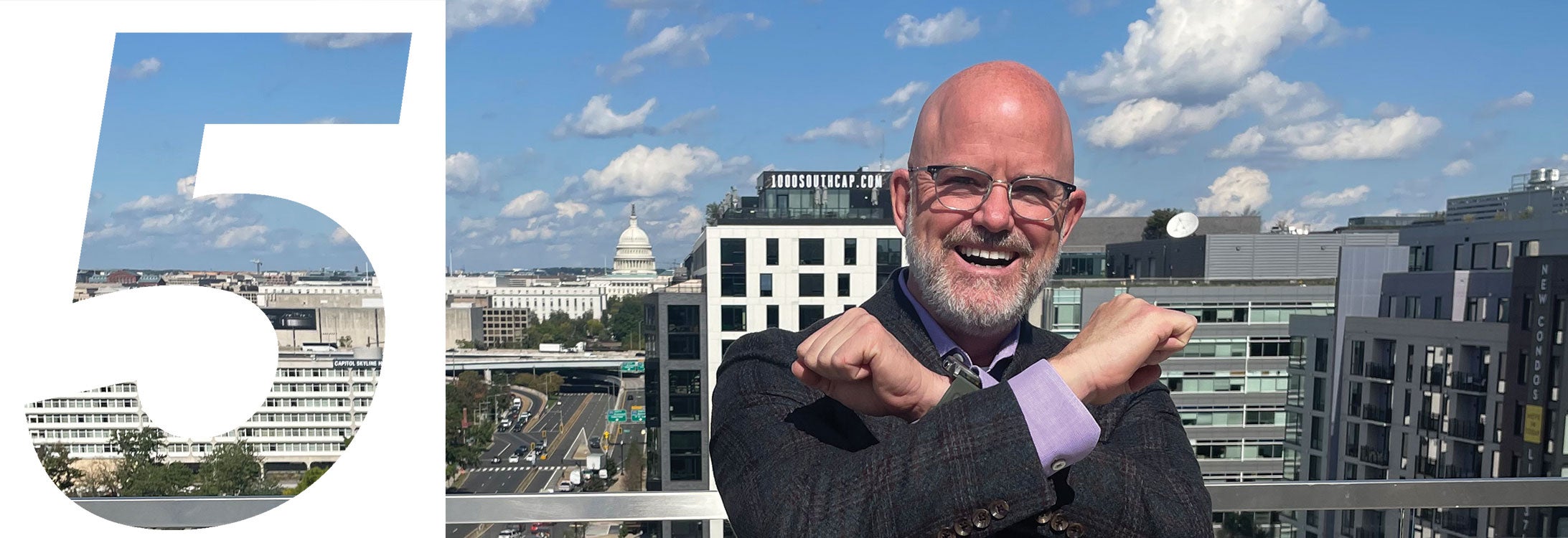 A man with glasses and a beard stands on a balcony, overlooking a vibrant city skyline in the background.