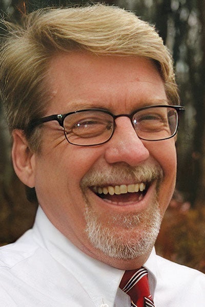 A man in glasses laughing.