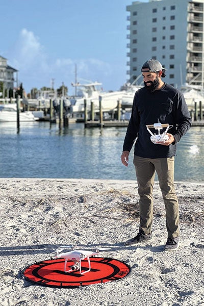 A man with a drone on the sand.