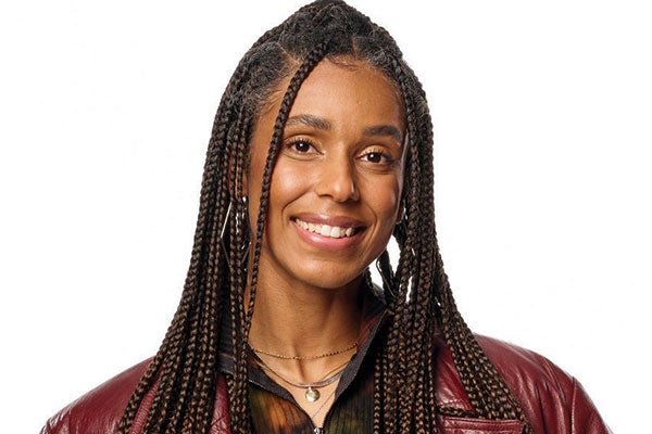 A woman with braids is confidently wearing a striking red leather jacket. 