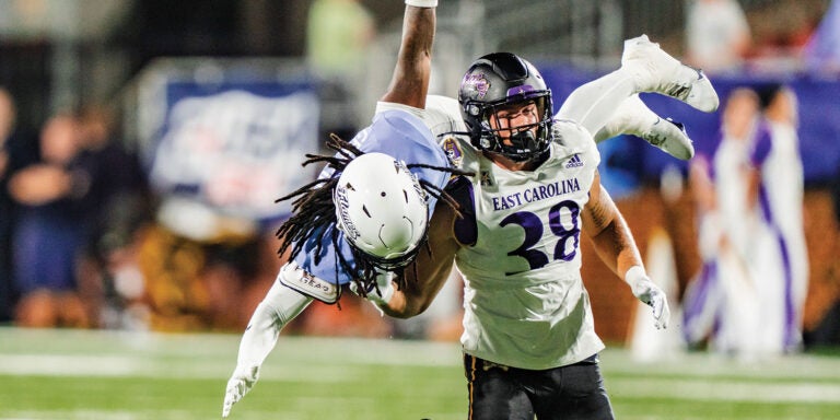 A football player grips another player tightly during a competitive match on the field.