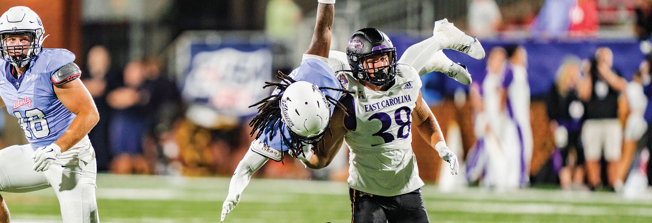 A football player grips another player tightly during a competitive match on the field.