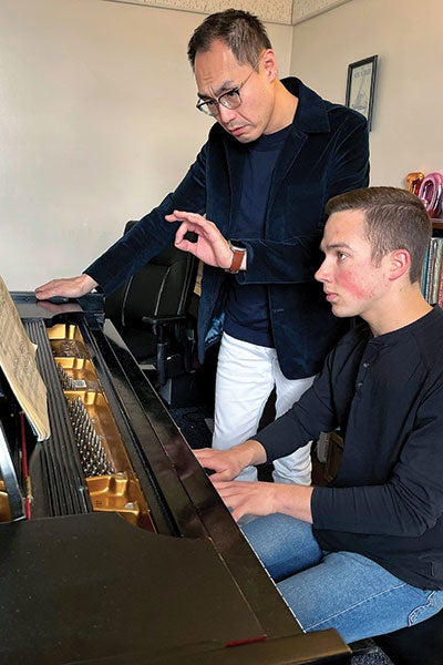 A professor teaches a student piano.