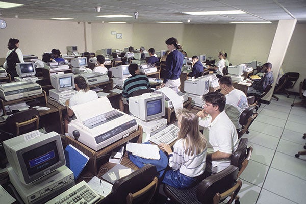 Several people seated at desks, engaged with their computers, creating a productive workspace atmosphere.