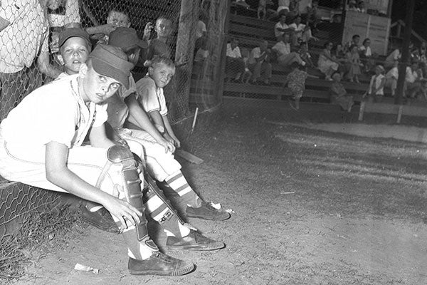 Several people of varying ages and backgrounds sitting on a bench, sharing a moment of camaraderie in a park setting.