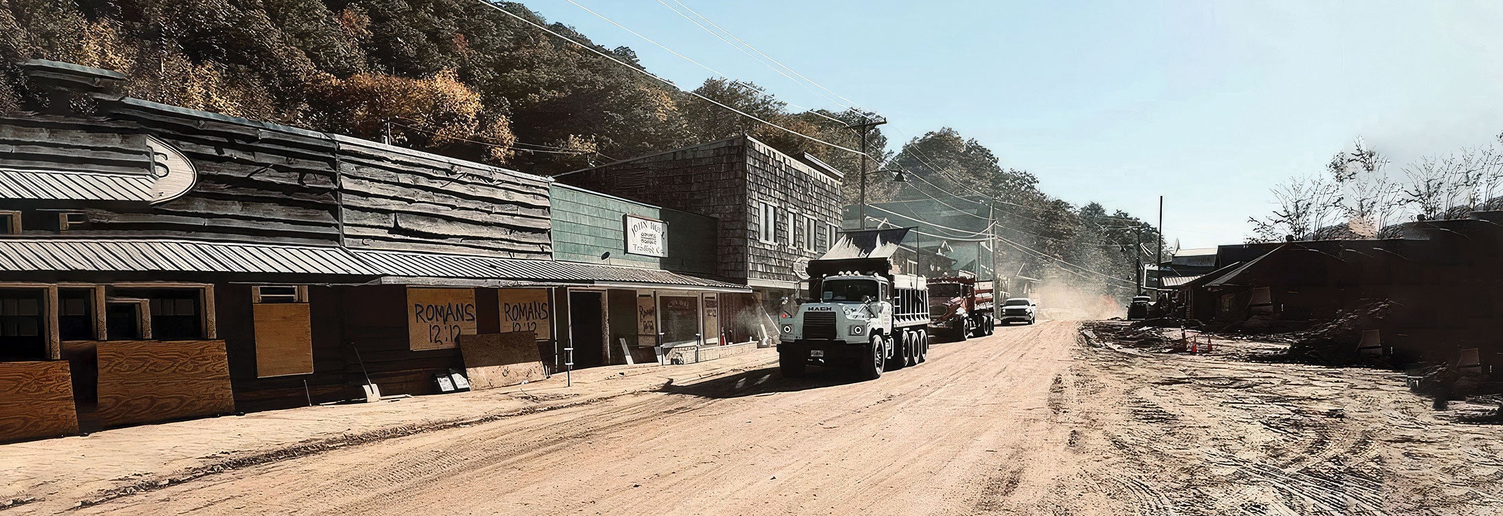 Dump truck drives down a dusty road.