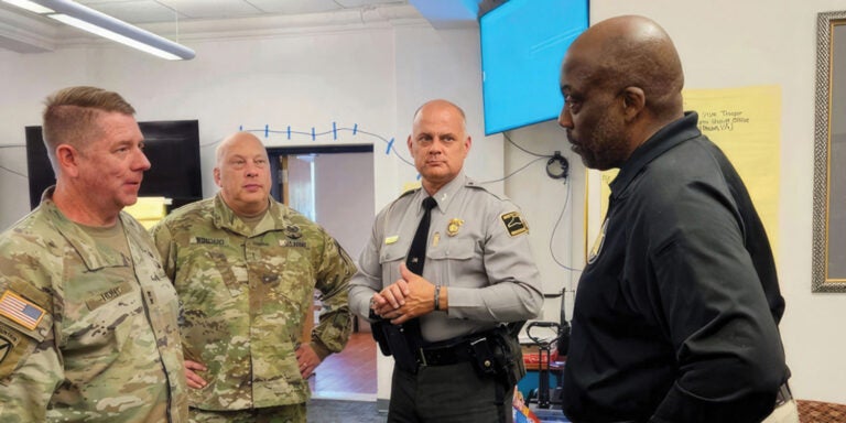 Four military personnel engaged in conversation within a room, discussing matters of importance and strategy.