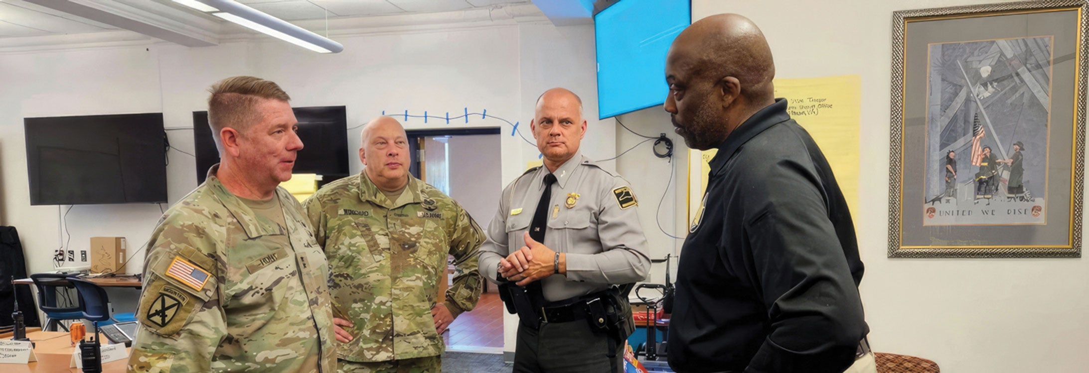 Four military personnel engaged in conversation within a room, discussing matters of importance and strategy.